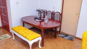 Een eetgedeelte met een houten tafel, stoelen en een bank.