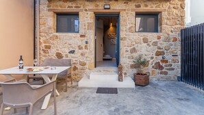 Ein Steinhaus mit einer kleinen Terrasse, einem Tisch mit Stühlen und einem Blumentopf.