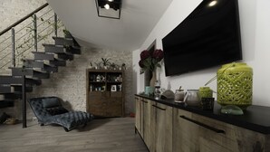 Moderni olohuone, jossa on portaikko, litteänäyttöinen televisio ja puinen kaappi.
