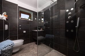 Un baño moderno con ducha vidriada, inodoro y lavamanos.