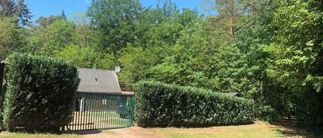 A fenced property with a small building, surrounded by dense greenery and trees.