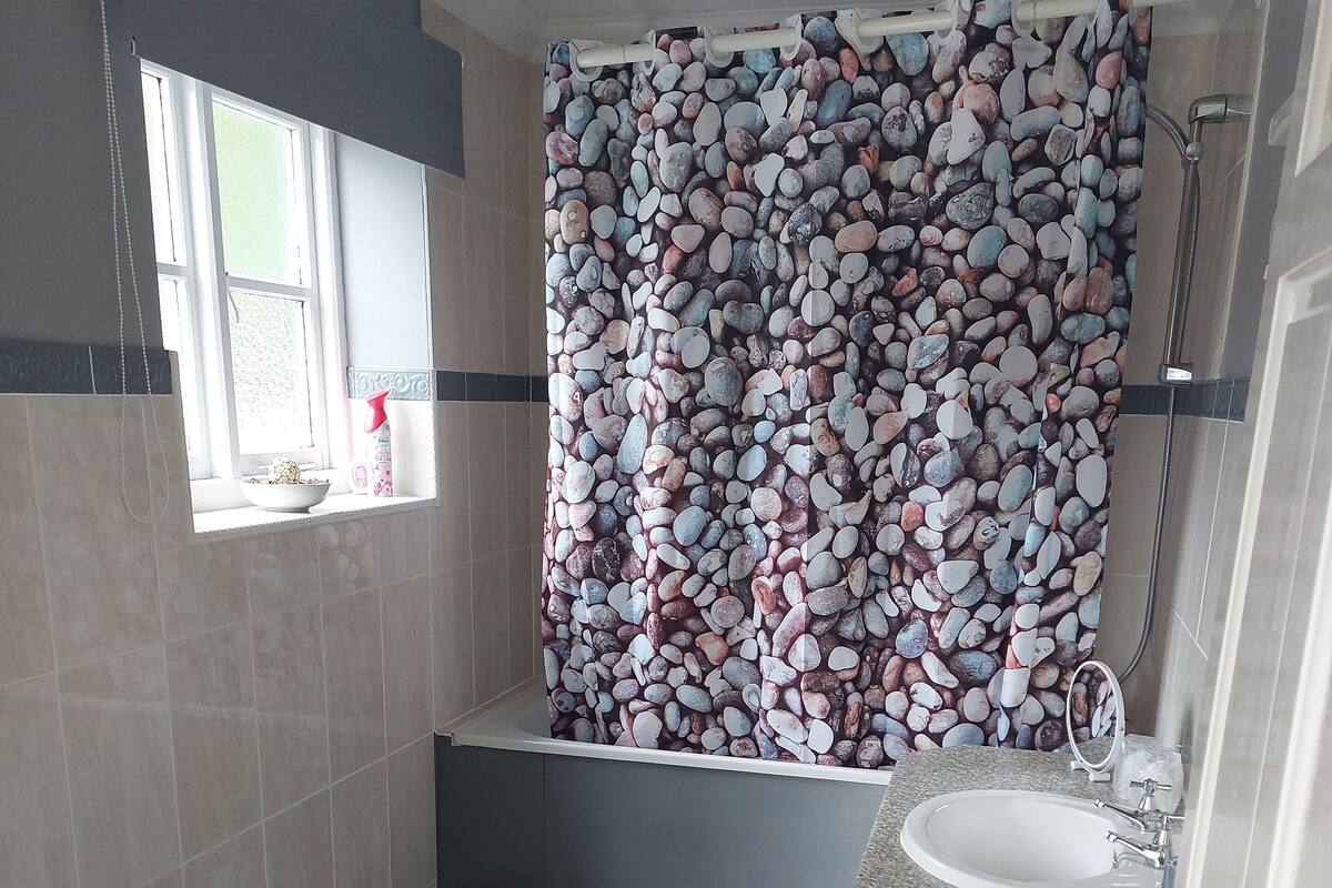 A bathroom with a shower curtain featuring a pebbles pattern, a sink, and a toilet.