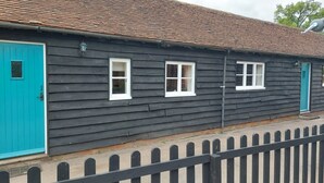 Une rangée de maisons en bois sombre, avec des fenêtres à cadre blanc et une porte bleue.