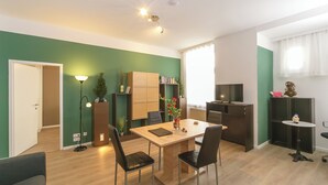 Eine moderne Küche mit Essbereich, Holzschränken, einem Fernseher und einem kleinen Tisch mit Stühlen.