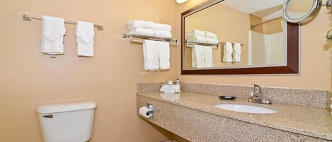 A hotel bathroom with a toilet, sink, and multiple towel racks.