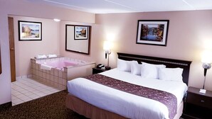 A hotel room with a large bed, a separate bathroom with a bathtub, and two framed pictures on the walls. - Quality Inn & Suites Black River Falls I-94 (Black River Falls)