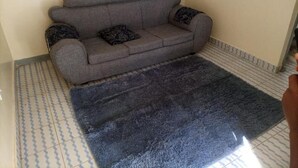 A grey sofa with patterned cushions in a room with tiled flooring.