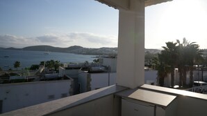 Un balcon avec vue sur la mer et les collines lointaines.