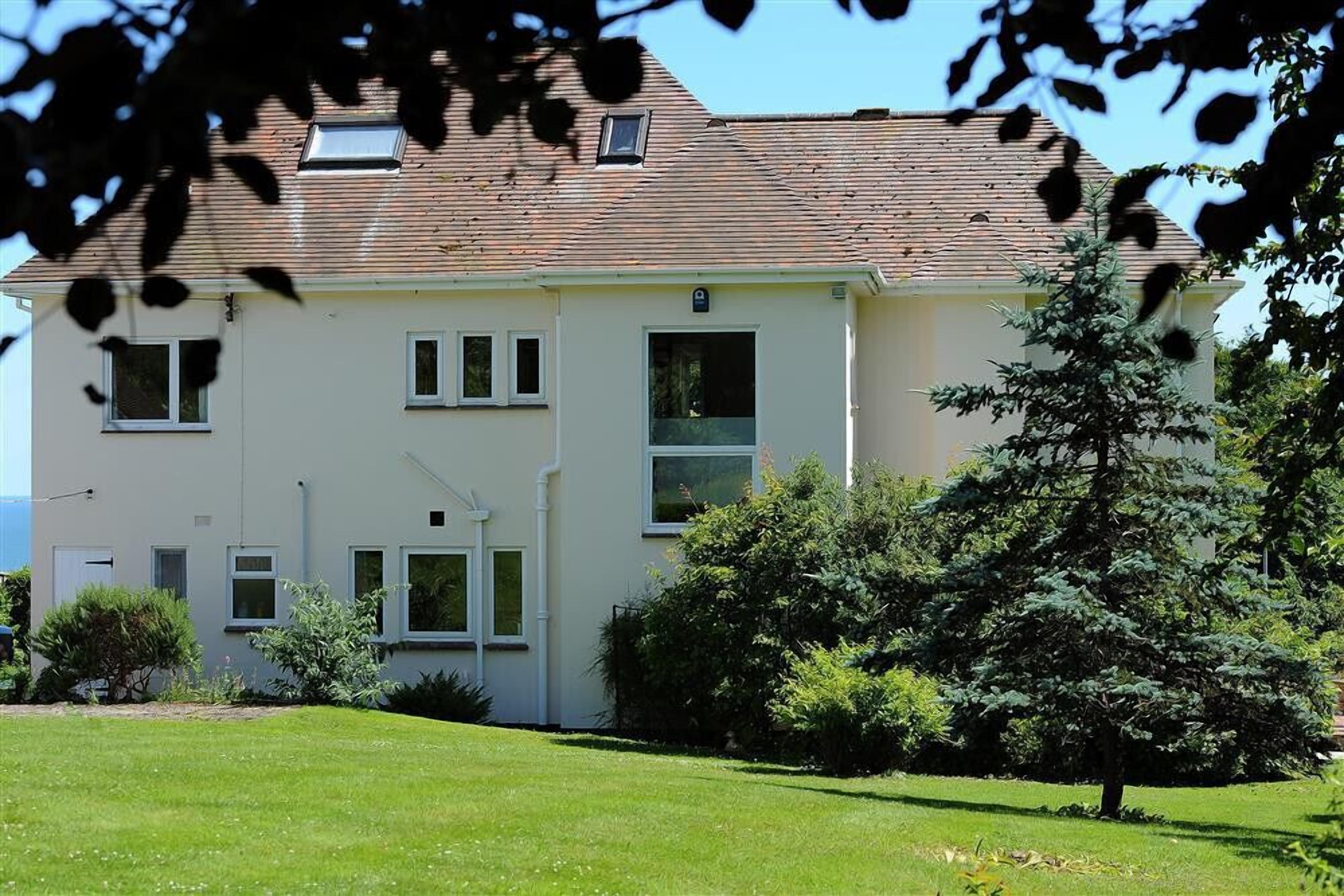 A two-story building with a flat roof, multiple windows, and a well-maintained lawn.