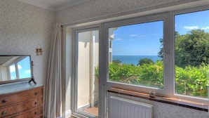 A room with a large window offering a view of the sea and greenery. - Westdale Edge (Seaton)