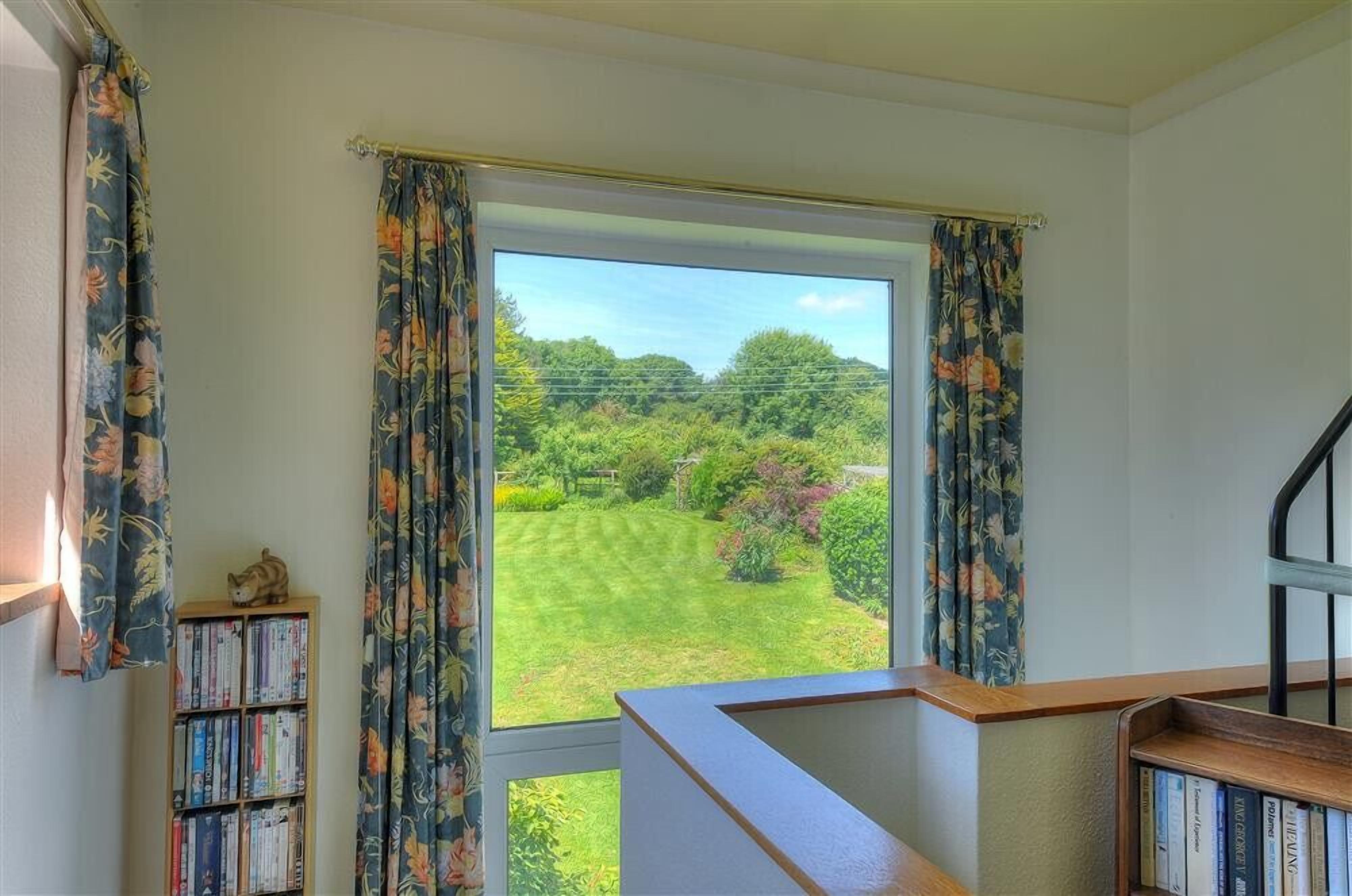 A room with a large window offering a view of a well-maintained garden.