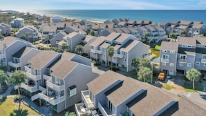 A coastal residential area with modern multi-story buildings, balconies, and a view of the ocean. - Barrier Dunes 426 - 62 Beach House Too (Port St. Joe)