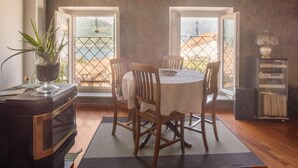 Un coin repas avec une table ronde, des chaises en bois, une plante en pot et un four ancien.