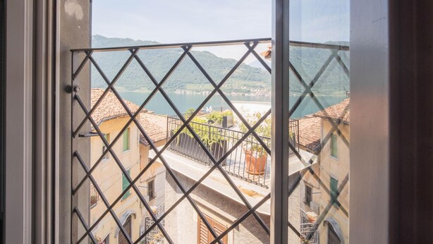 Un balcon doté d’une balustrade en métal, donnant sur une ville et un lac.