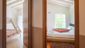 Une chambre à coucher avec un lit, une fenêtre et un escalier menant à une pièce située à l’étage.