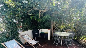 A wooden deck with a table and chairs, surrounded by lush greenery. - COTE BASQUE BIDART Apt, terrace, gardin, BBQ, Surf, near beach, all shops  (Bidart)