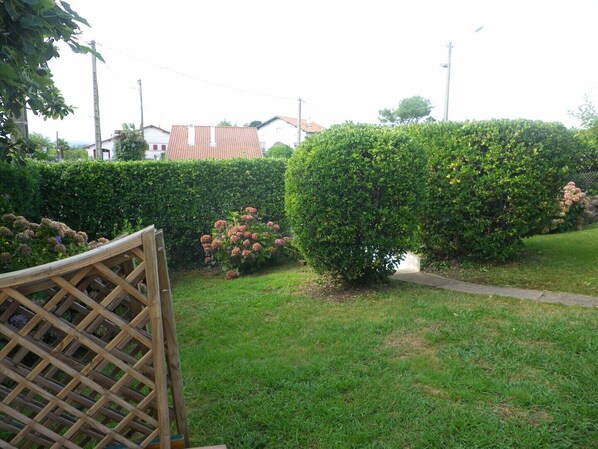 A well-maintained garden with neatly trimmed hedges and a wooden lattice structure. - COTE BASQUE BIDART Apt, terrace, gardin, BBQ, Surf, near beach, all shops  (Bidart)