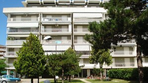 Ein mehrstöckiges Hotel mit Balkonen, einem Parkplatz und einem gepflegten Rasen.