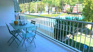 Ein Balkon mit Tisch und Stühlen, Blick auf einen Swimmingpool und ein Gebäude im Hintergrund.