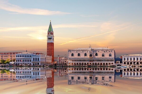 A historic building with a prominent tower and a large courtyard with a reflective water surface.
