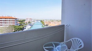 Un balcon donnant sur une marina, une chaise blanche et une petite table.