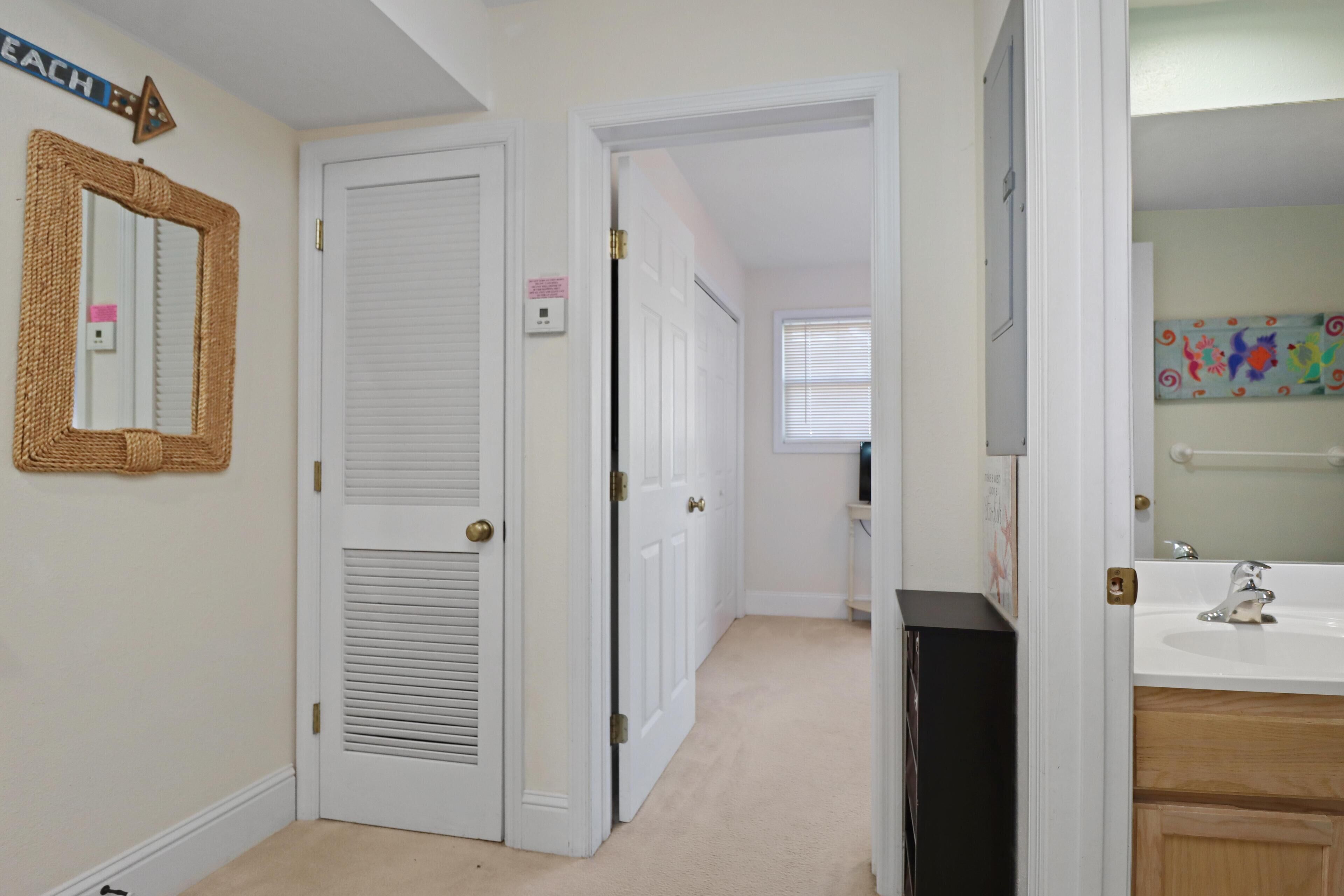 A hallway with white doors, a mirror, and a black speaker.