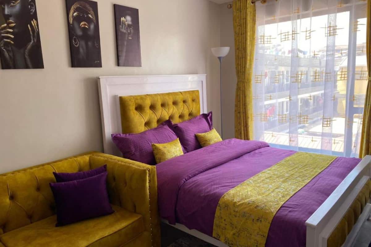 Une chambre à coucher avec un lit, un canapé et une fenêtre avec des rideaux.