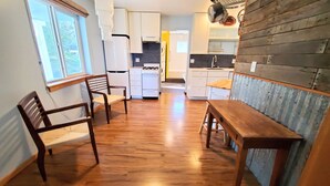 Una cocina con suelo de madera, armarios blancos, estufa y pileta.
