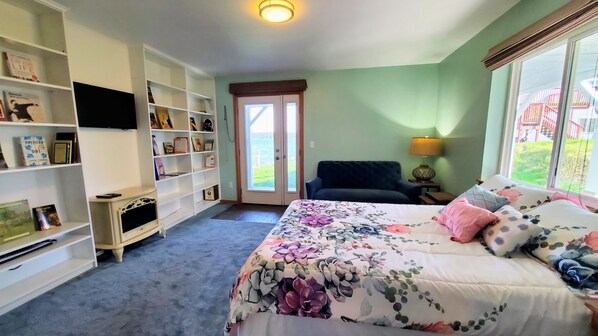 Un dormitorio con cama, una estantería, una silla y ventana con vistas.