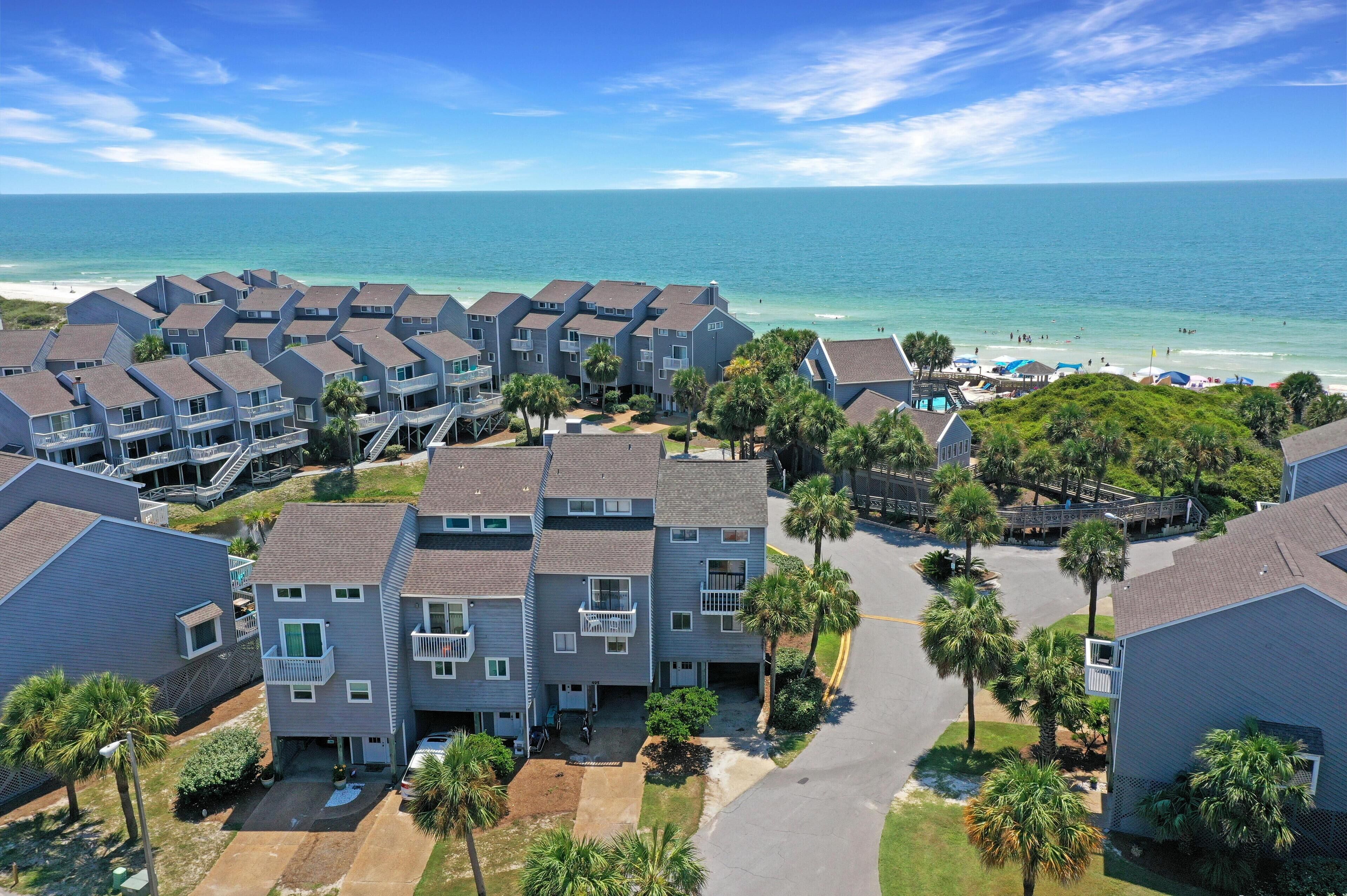 A coastal residential area with multiple two-story buildings, a beach, and a pool area.