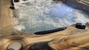 A hot tub with a wooden exterior, a control panel, and a view of the bathroom area. - Gîte 10pers Avec Jacuzzi & Sauna Privatifs (Blainville-sur-Mer)