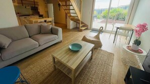 Amplia sala de estar con sofá, mesa de centro y escalera que lleva a un nivel superior.