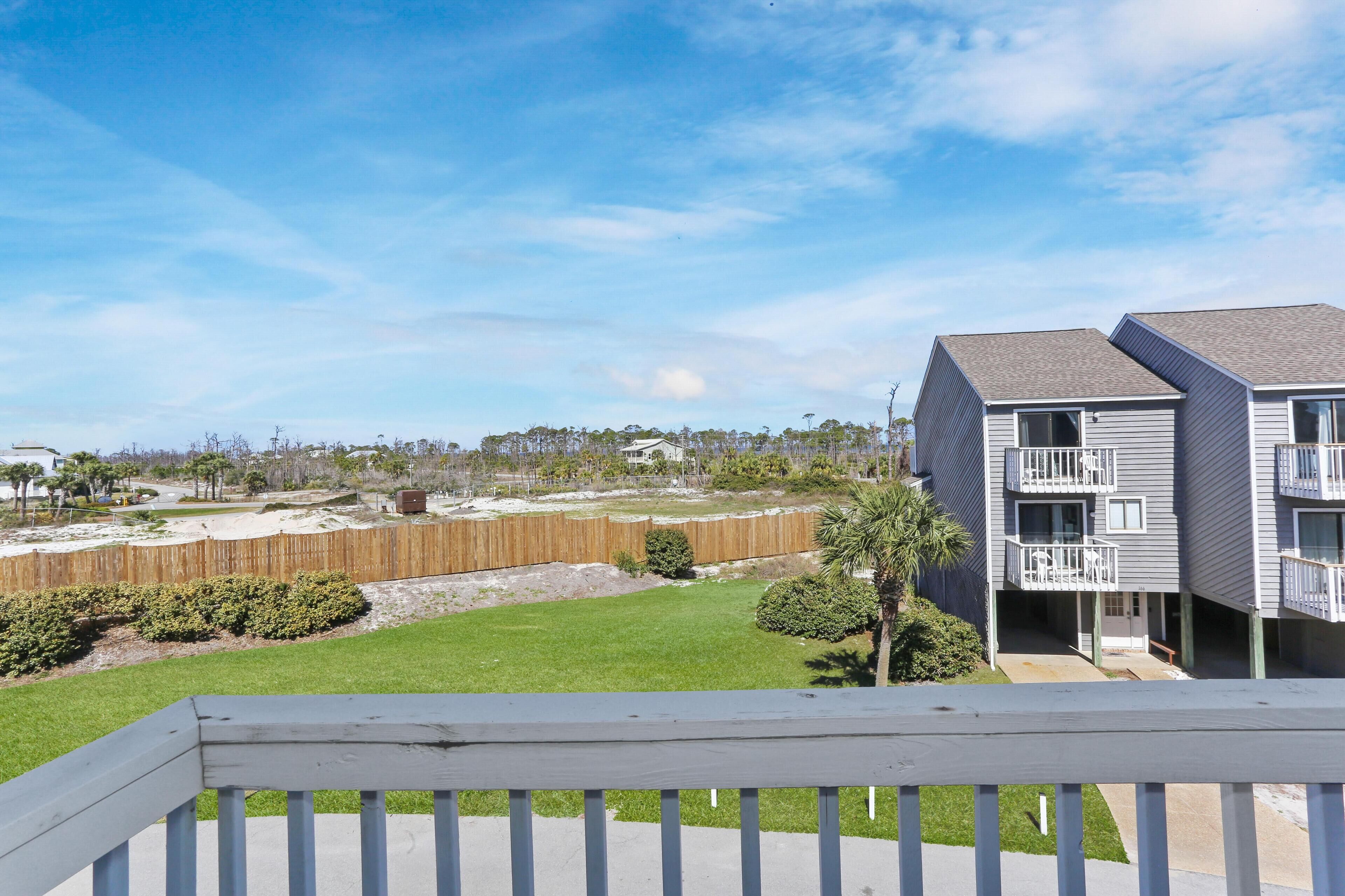 A residential building with a balcony, a fenced yard, and a clear sky.