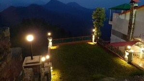 A night view of a building with a red roof and a stone wall. - Veenu's Cottage (Dehradun)