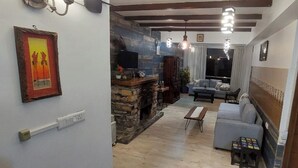 A living room with a fireplace, a sofa, and a television. - Veenu's Cottage (Dehradun)