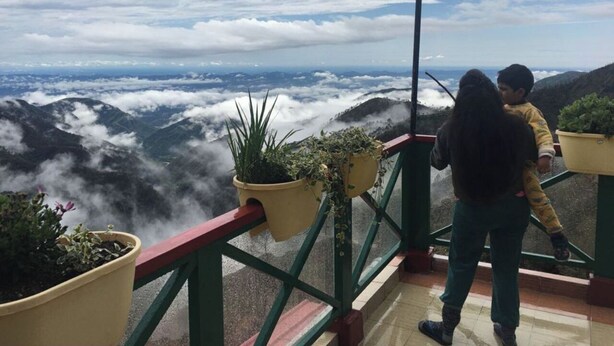 A balcony with potted plants and a view of a mountainous landscape. - Veenu's Cottage (Dehradun)