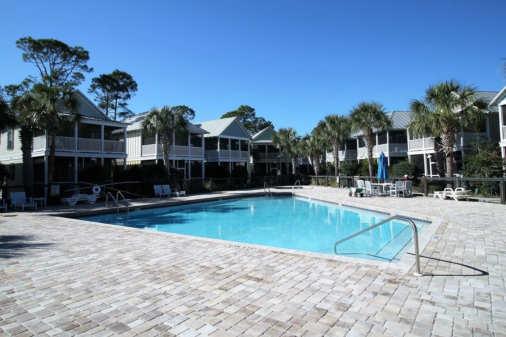 A swimming pool with lounge chairs and a brick patio.