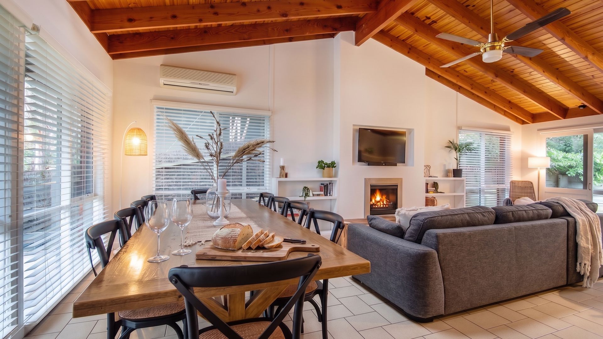 A spacious living area with a wooden ceiling, a fireplace, a flat-screen TV, and a comfortable seating arrangement.