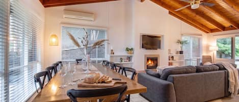 A spacious living area with a wooden ceiling, a fireplace, a flat-screen TV, and a comfortable seating arrangement.