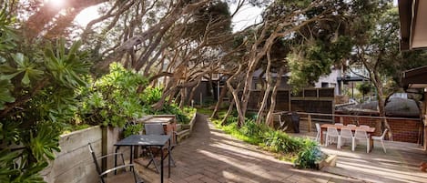 A patio area with a brick floor, outdoor furniture, and a variety of plants.