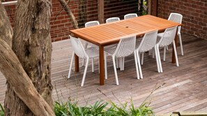 Una mesa de madera con sillas blancas sobre una terraza de madera.