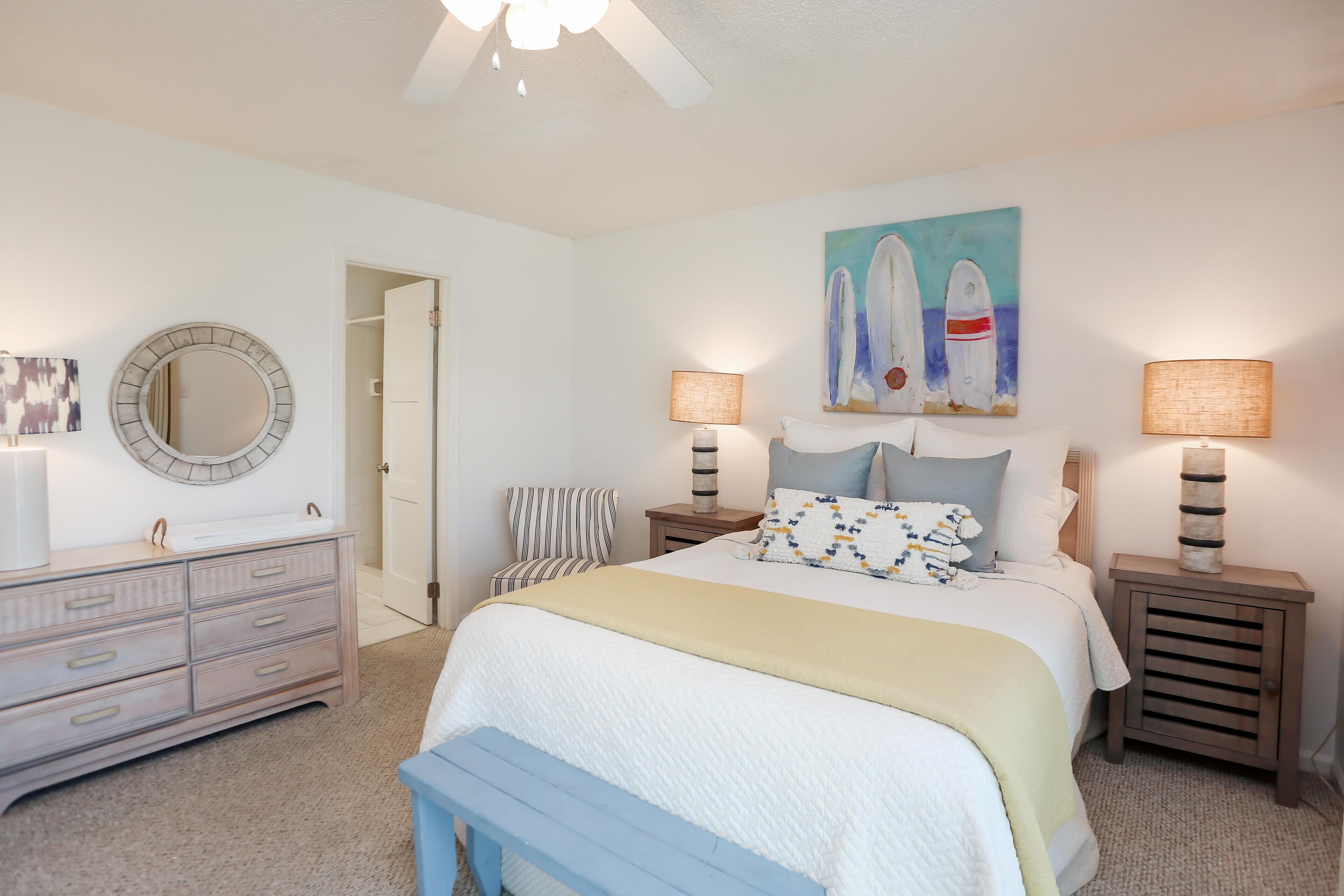 A bedroom with a bed, bedside tables, a dresser, a chair, a mirror, and a painting on the wall.
