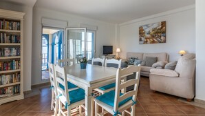 Un salón espacioso con comedor, sofá, televisión y estantería.