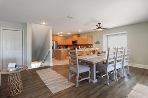 A spacious kitchen with wooden cabinets, a central island, and a dining area with a table and chairs. - Barrier Dunes 248 - 111 Endless Summer (Port St. Joe)