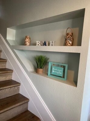 A staircase with wooden steps and a shelf above holding decorative items and a sign.