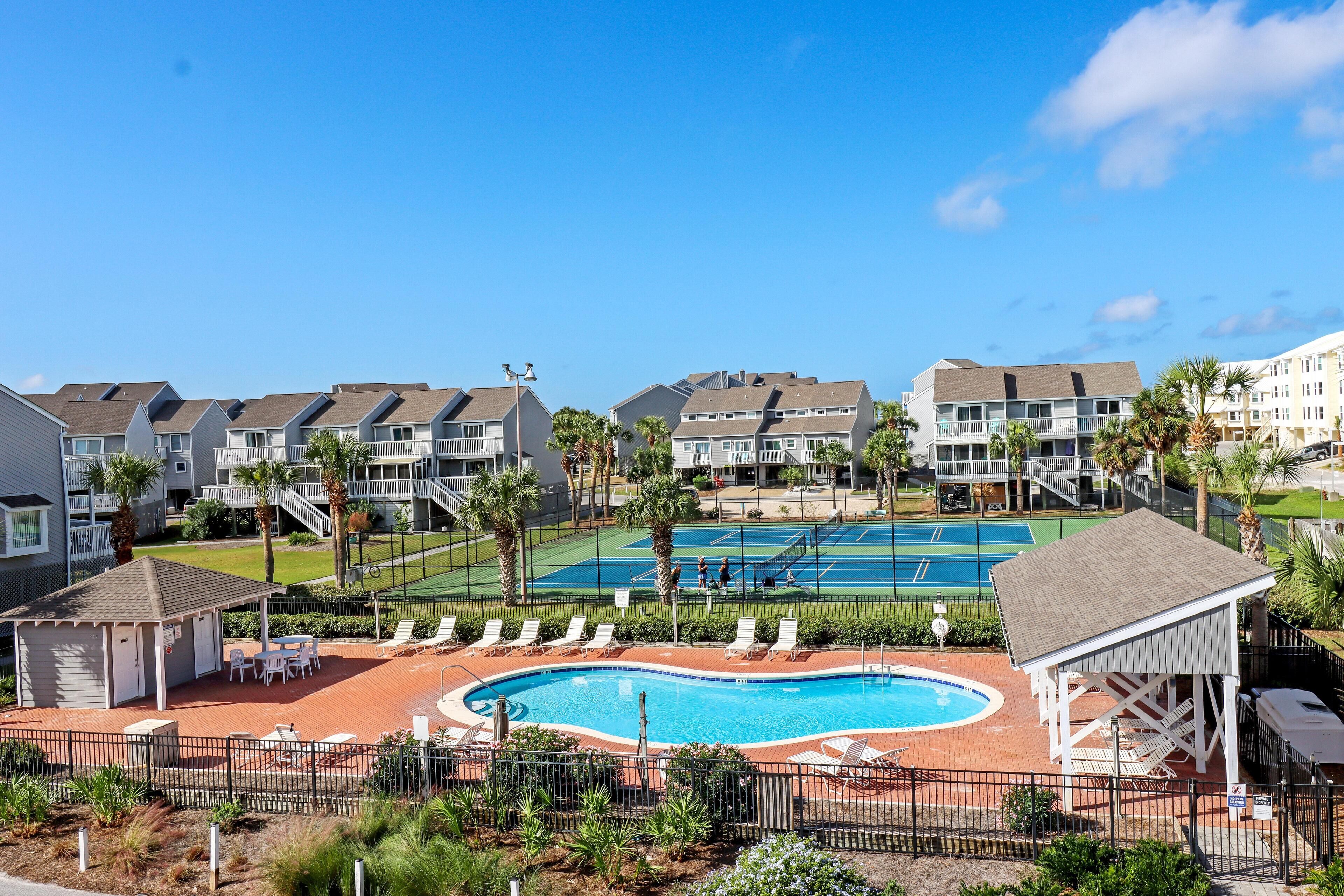 A pool area with lounge chairs and a small pool, surrounded by apartment buildings.