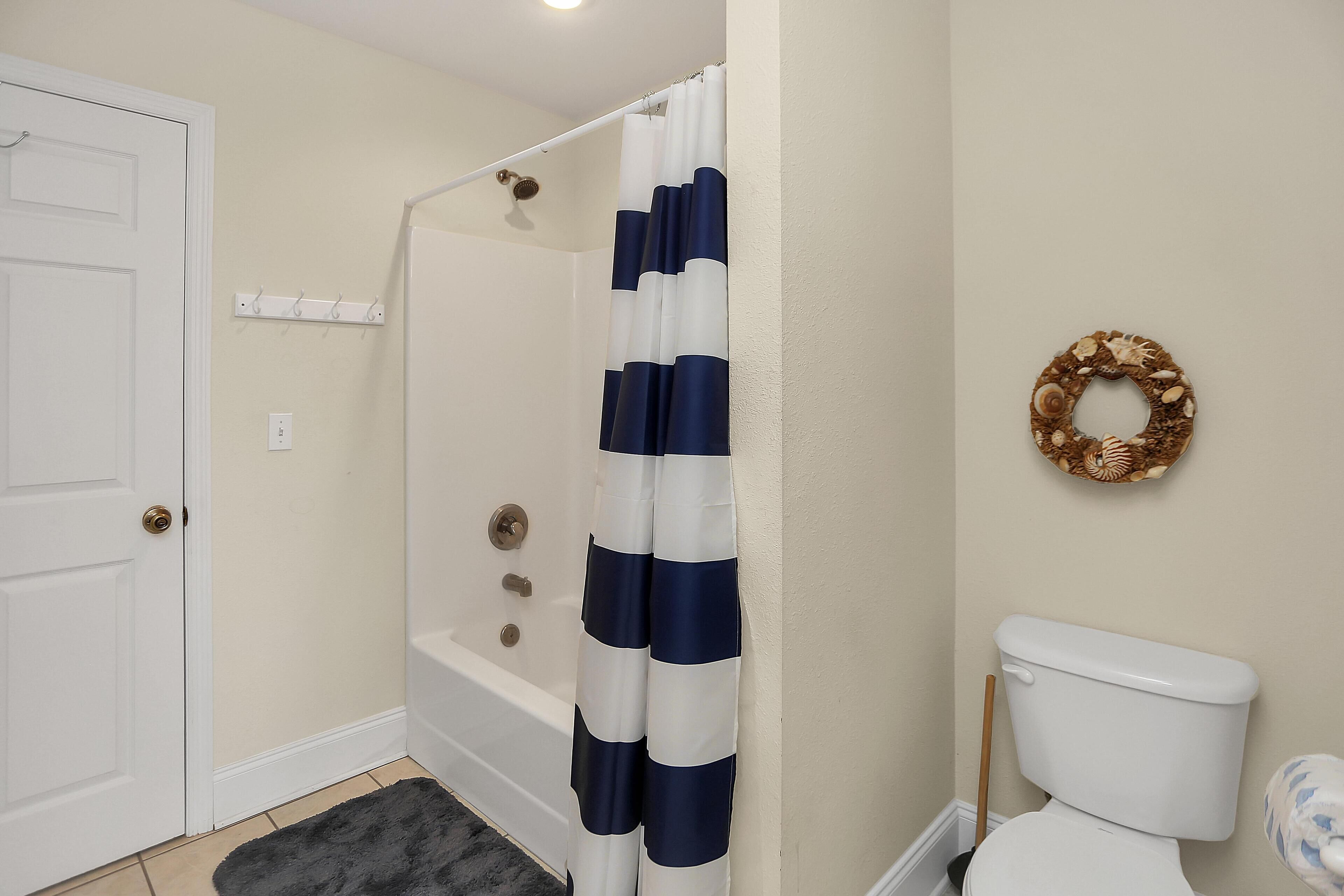 Een badkamer met douchegordijn, toilet en een decoratieve krans aan de muur.