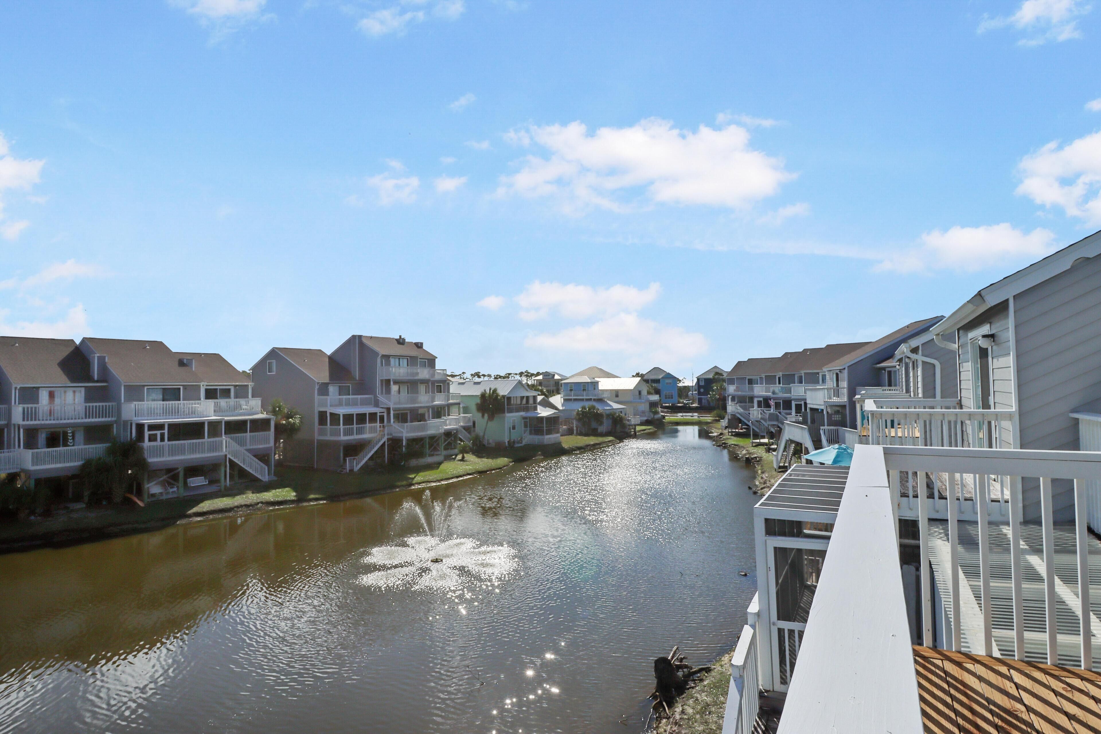 A canal with houses on either side, a wooden deck, and a clear sky.