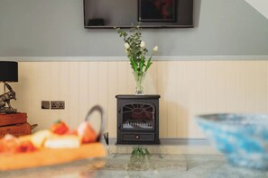 A kitchen with a stove, a vase with flowers, and a bowl of fruit on the counter. - Charming rural one-bedroom barn conversion (Grimsby)