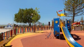 A playground with a slide, climbing structures, and a fenced area with benches. - Magnolia by Interhome (Olhão)